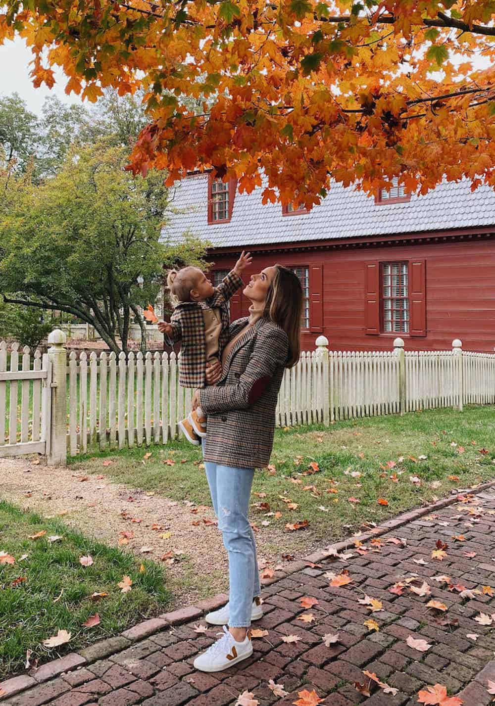 image of a mom holding her small daughter, wearing a plaid blazer, blue jeans, and sneakers