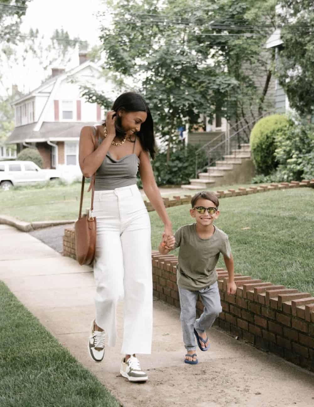 image of a woman and her son walking together, she is wearing white wide leg jeans, sneakers, and a green tank top