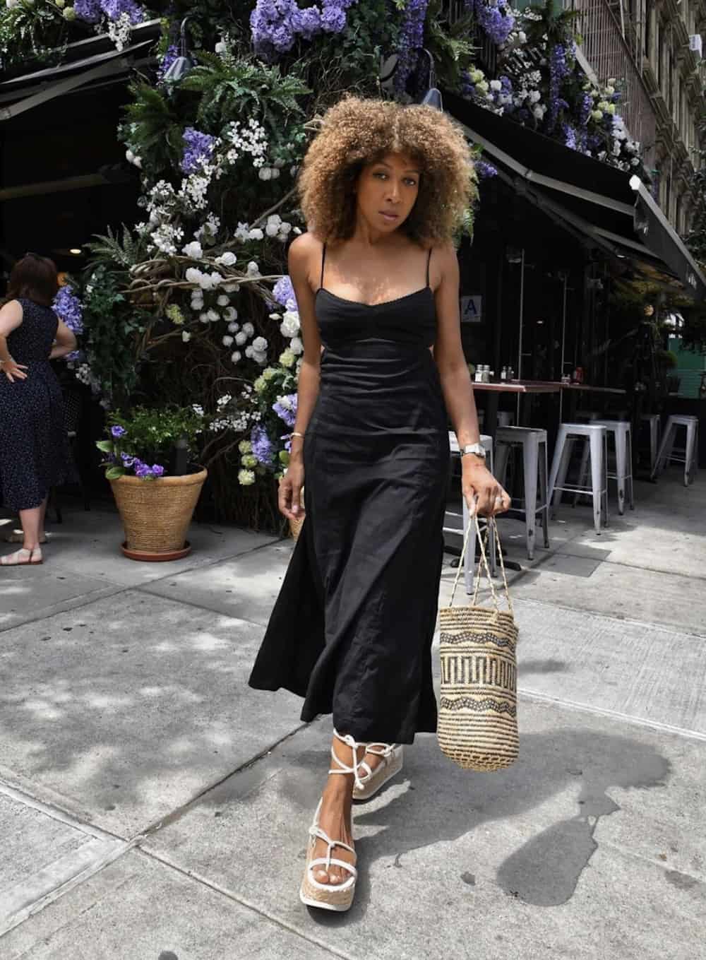 image of a black woman in a black long dress and white espadrille wedges