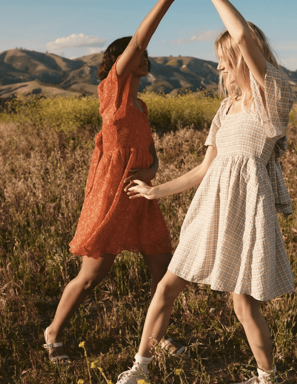 image of two young women dancing in a field wearing pretty summer dresses