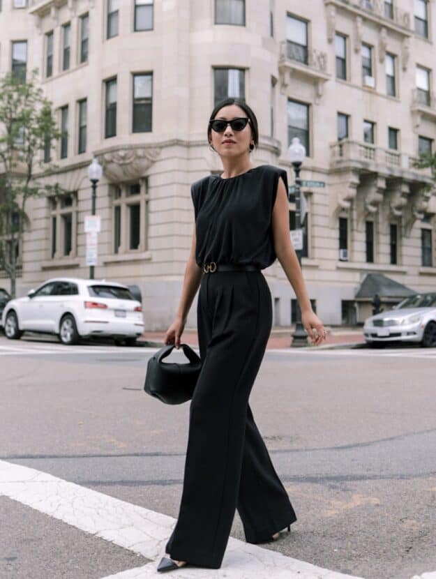 Woman wearing a black jumpsuit and heels.