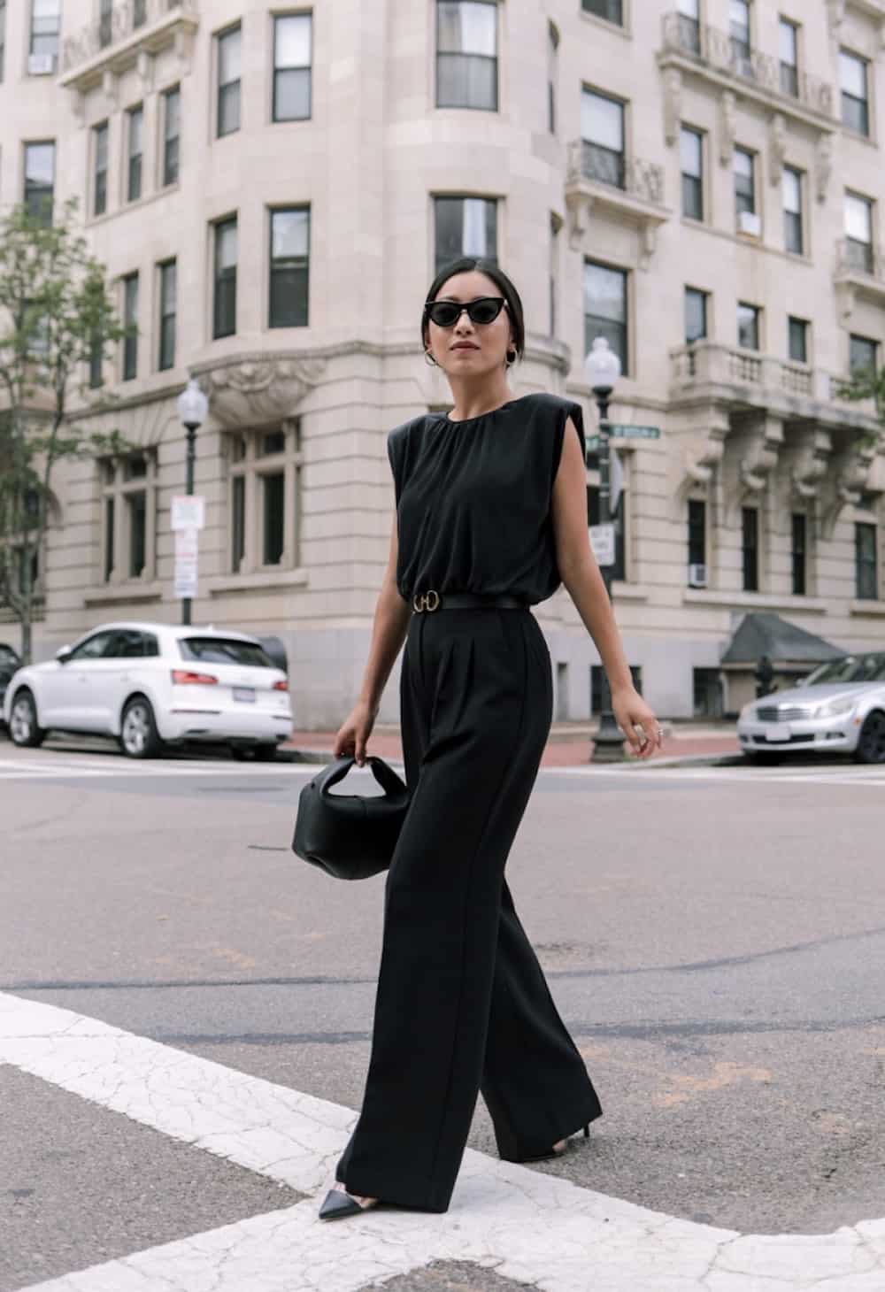 Woman wearing a black jumpsuit and heels.