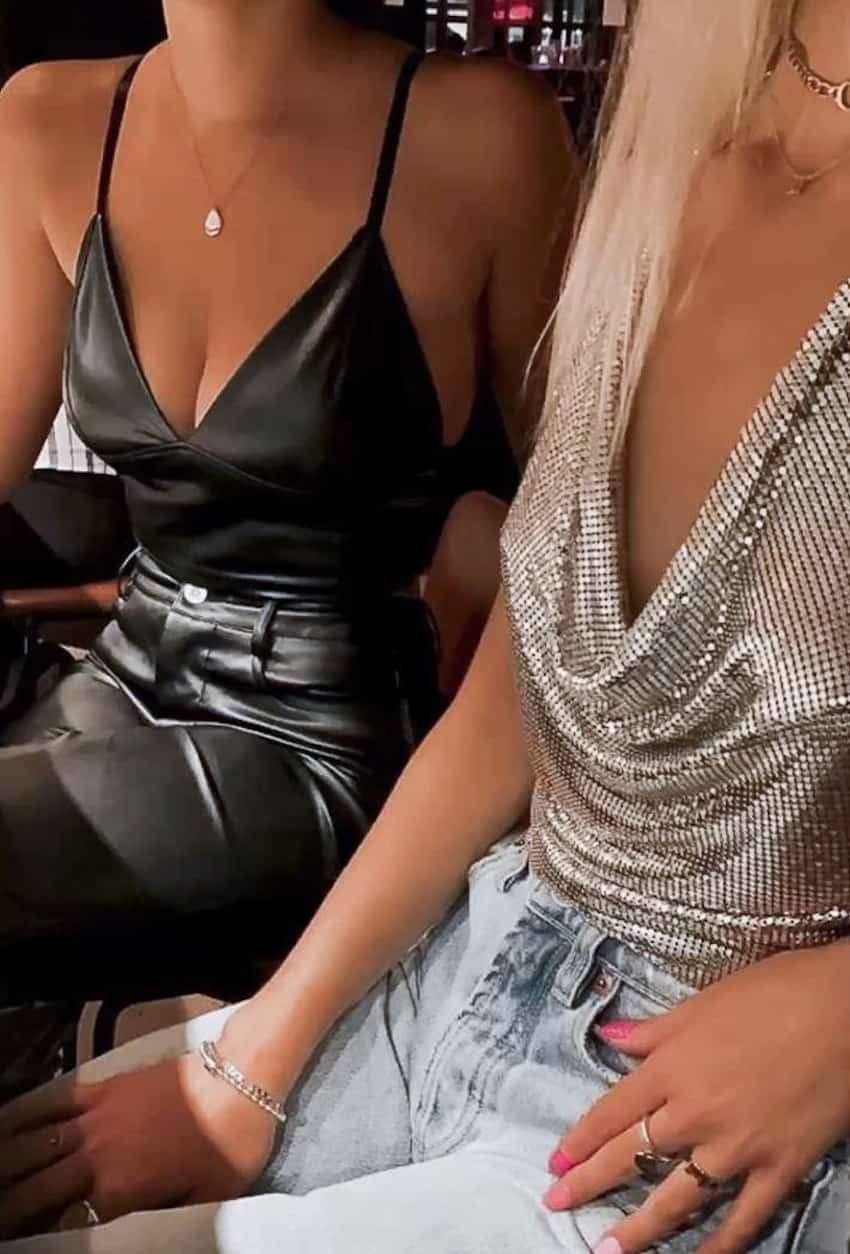 image fo two women wearing tank tops and black leather pants or jeans sitting at a chair 