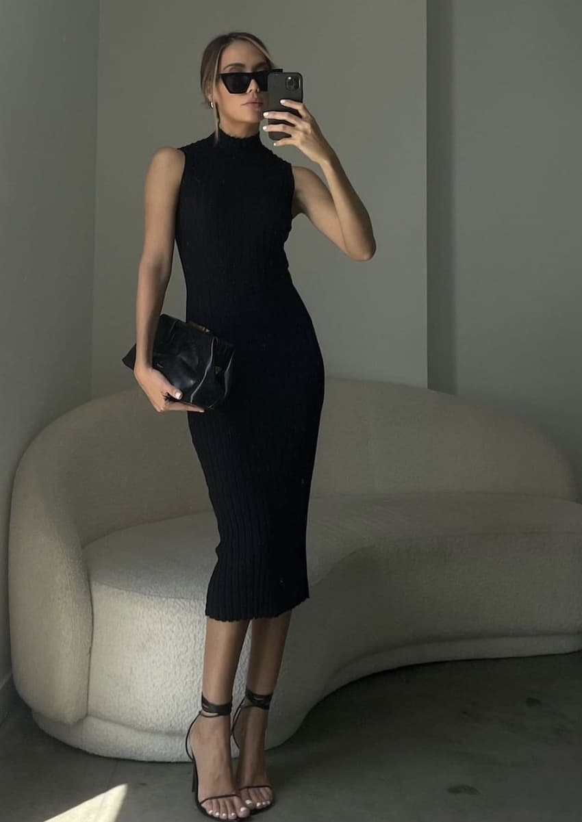 Woman wearing a tight, black midi dress.