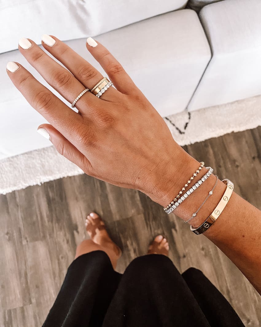 image of a woman's arm with a Cartier love bracelet and other pretty bracelets and rings