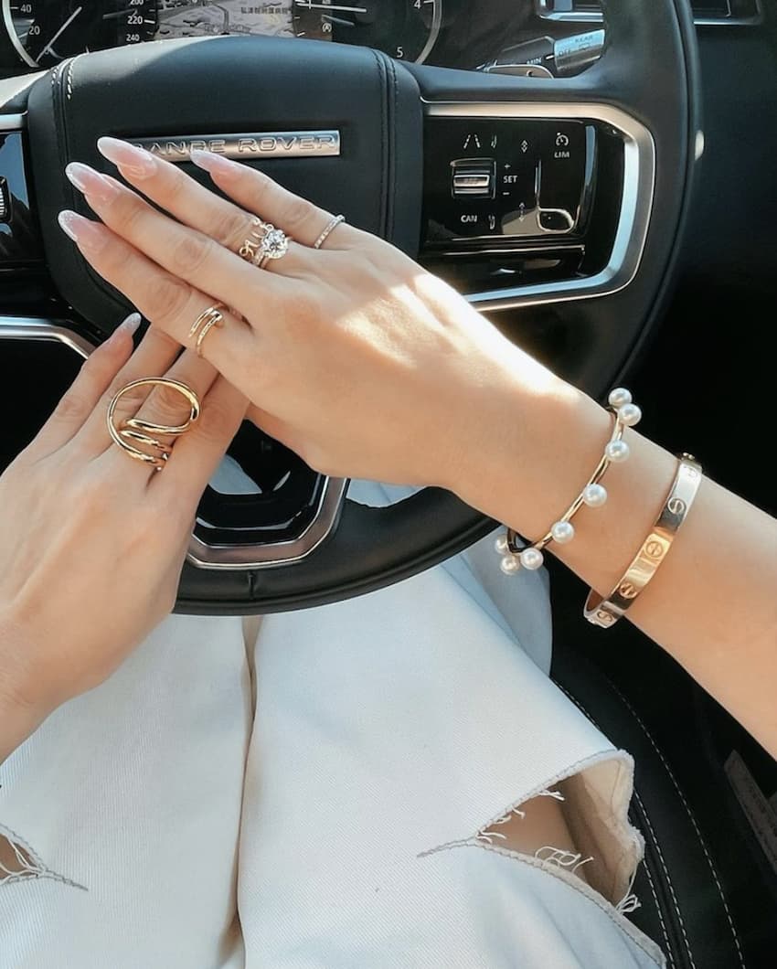 image of a womans arm with a Cartier bracelet and other designer jewelry