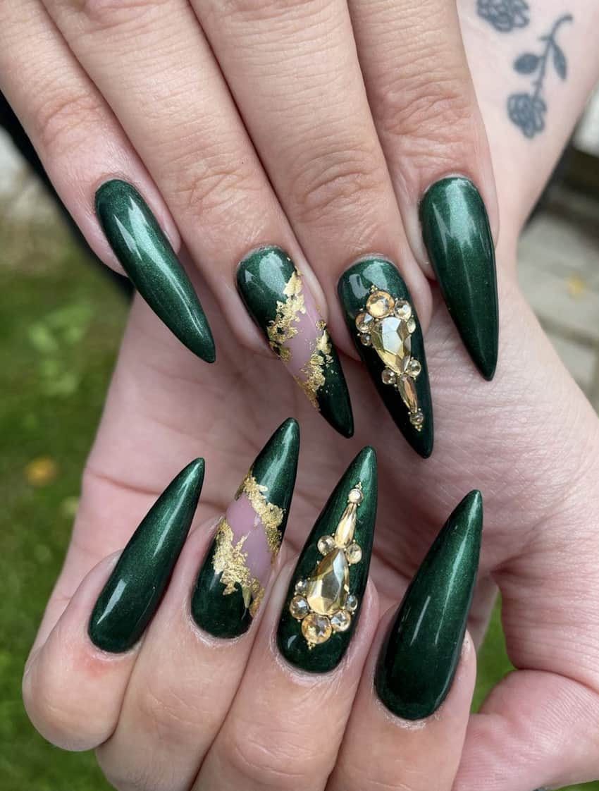 Long, pointed emerald green nails with gold embellishments.