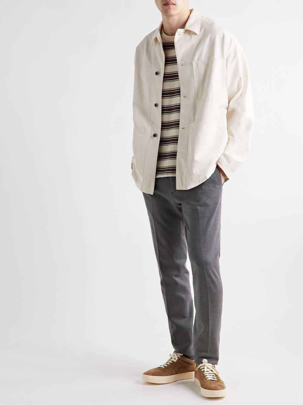 image of a man in grey pants, brown sneakers, a striped t-shirt, and ivory chore jacket