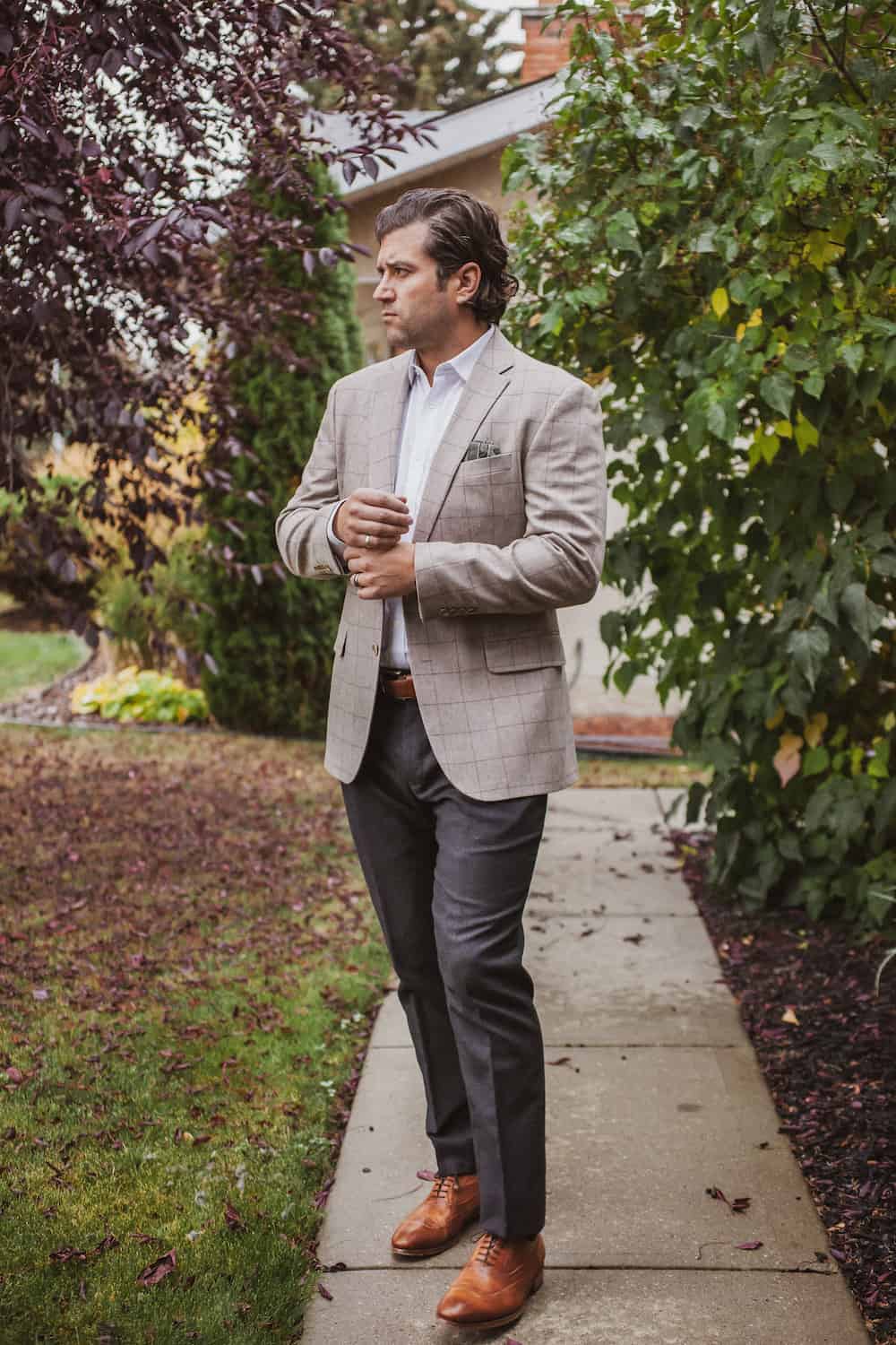 image of a man wearing a neutral plaid blazer, charcoal dress pants, cognac dress shoes, and a white button up shirt