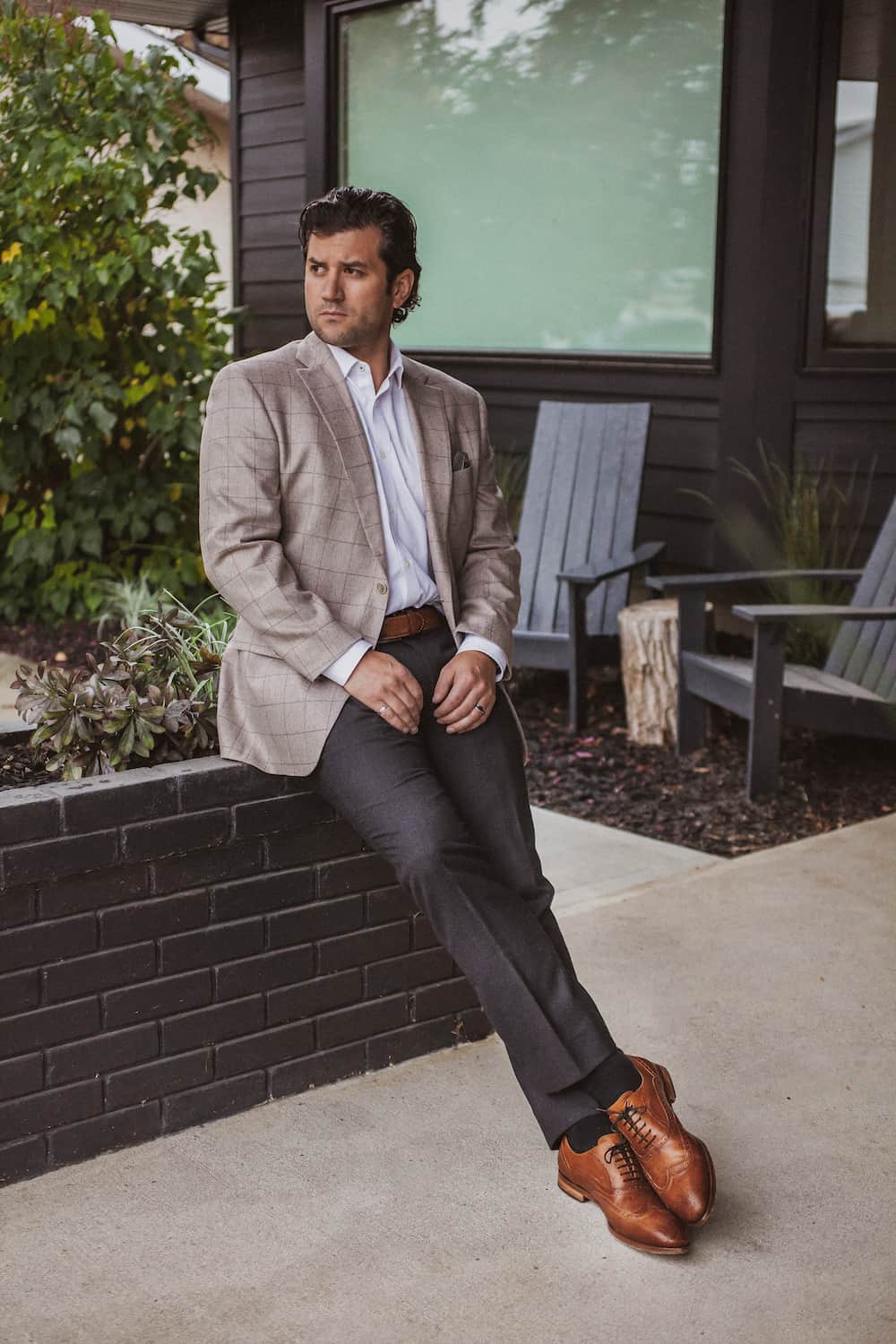 image of a man wearing a neutral plaid blazer, charcoal grey dress pants, brown dress shoes, and a white button up shirt