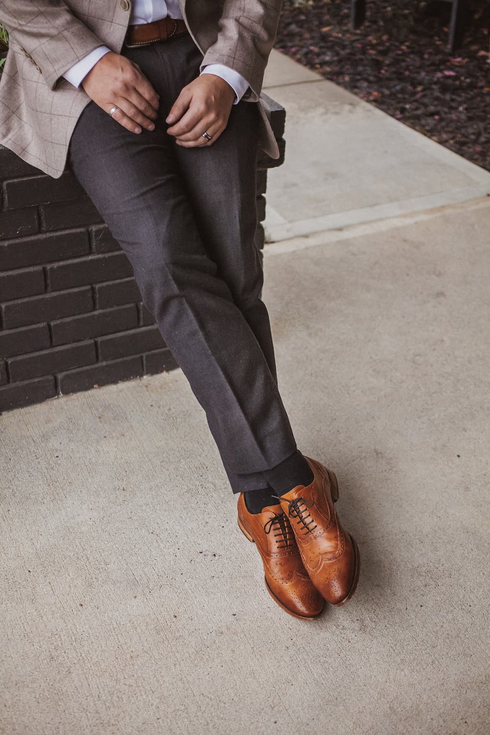 image of a mans legs wearing dark grey pants and brown dress shoes