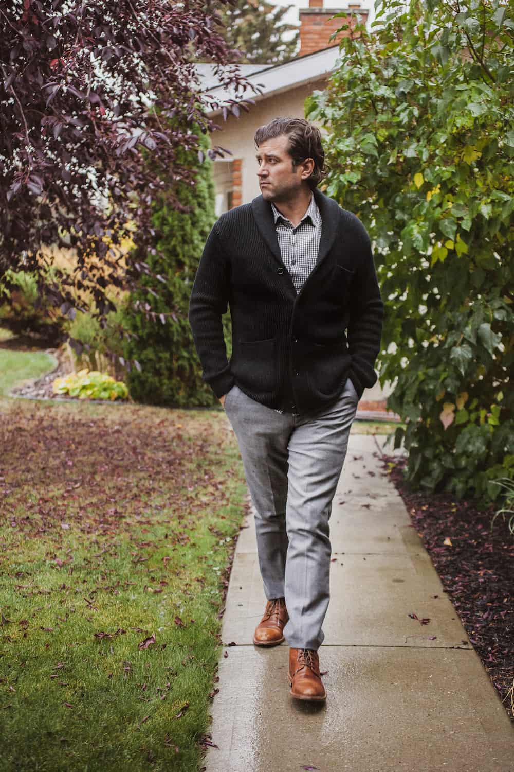 image of a man walking, wearing light grey pants, boots, and a black sweater