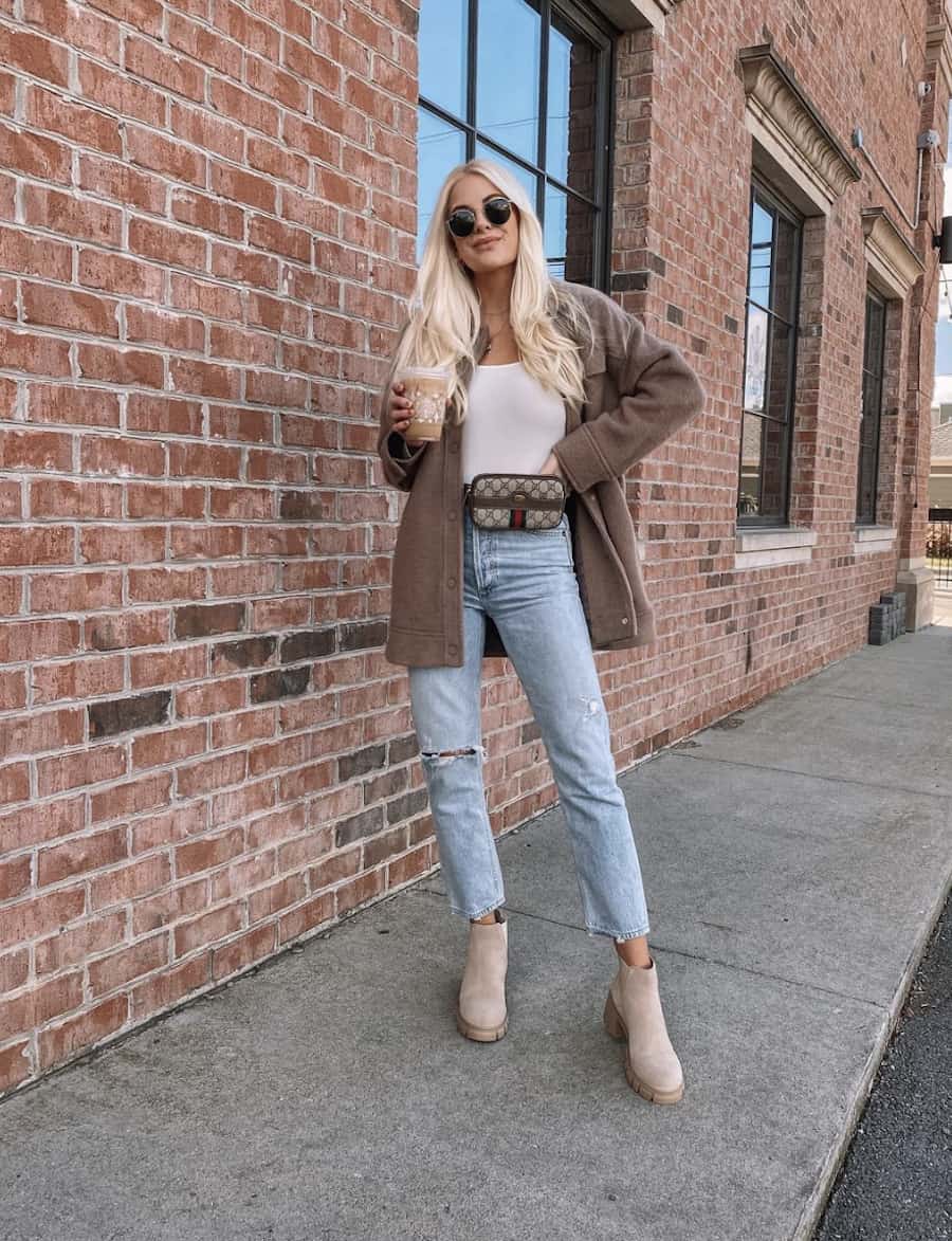 image of a woman in a pair of blue jeans, suede tan boots, fanny pack, and shirt jacket