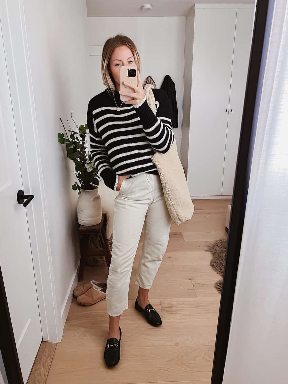 image of a woman in a black and white striped sweater, ivory jeans, and black loafers