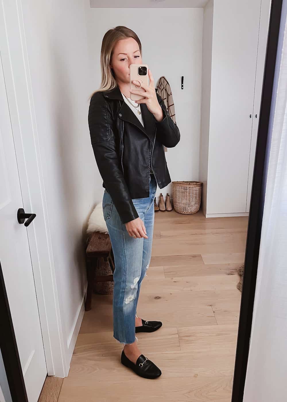 image of a woman wearing a black leather jacket, jeans, and black designer loafers