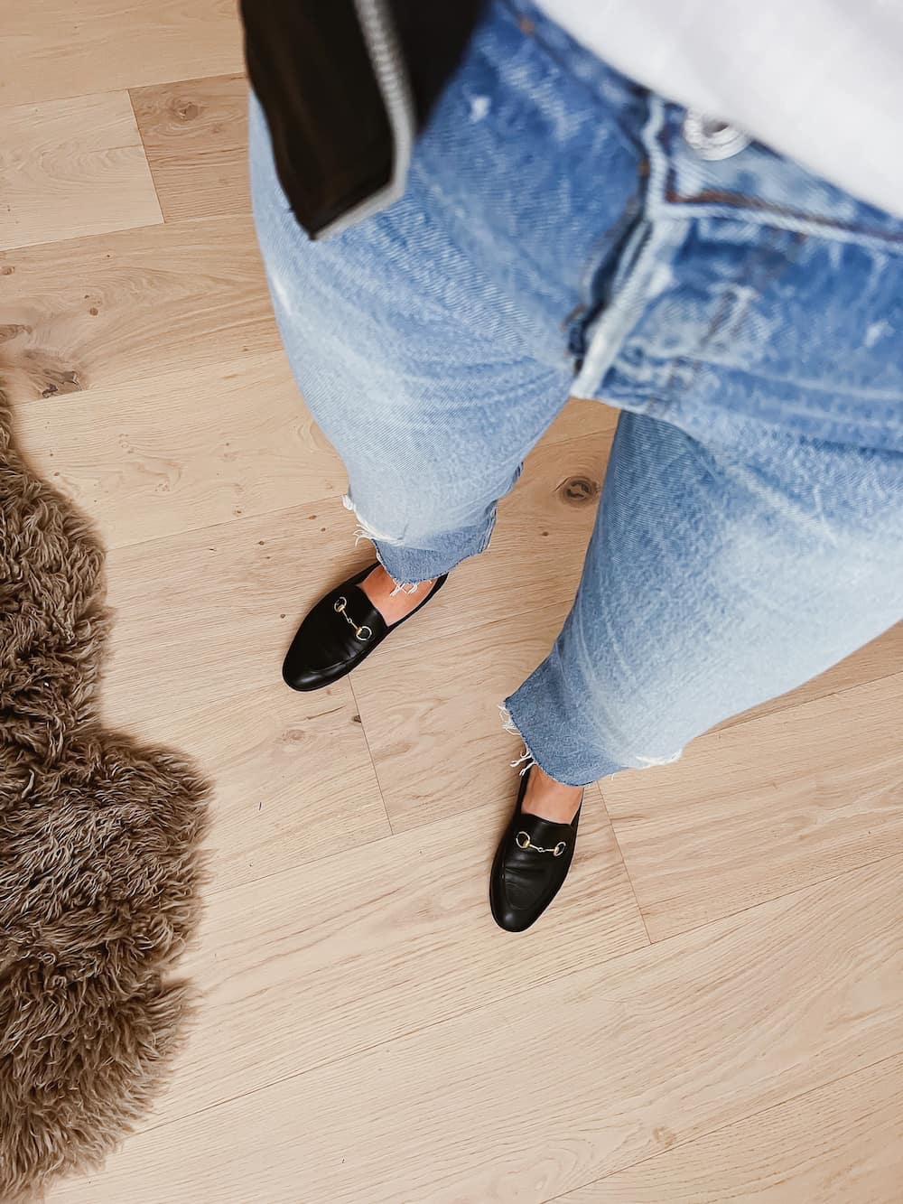 image of a woman's legs wearing blue jeans and black loafers
