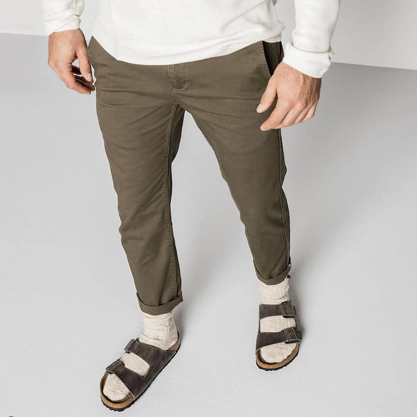 image of a mans lower body, wearing dark khaki chinos, socks, and Birkenstock sandals
