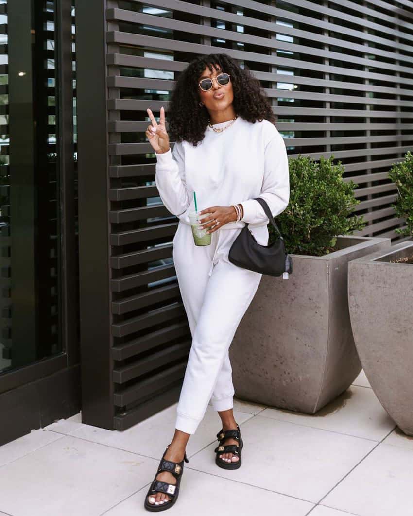 image of a black woman wearing a matching white sweatsuit with black dad sandals