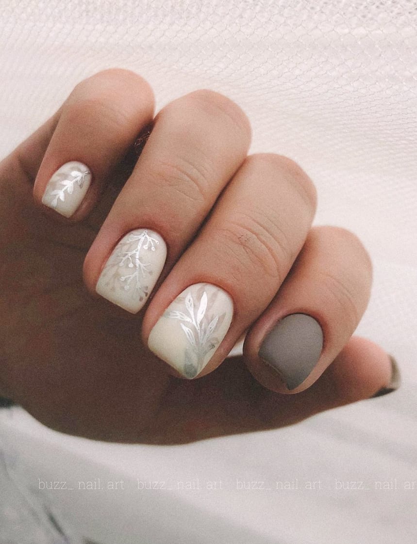 image of a hand with white Christmas nails with silver accents