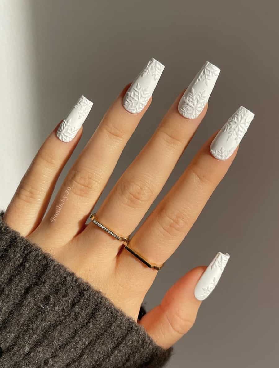 image of a hand with long white nails with a snowflake texture