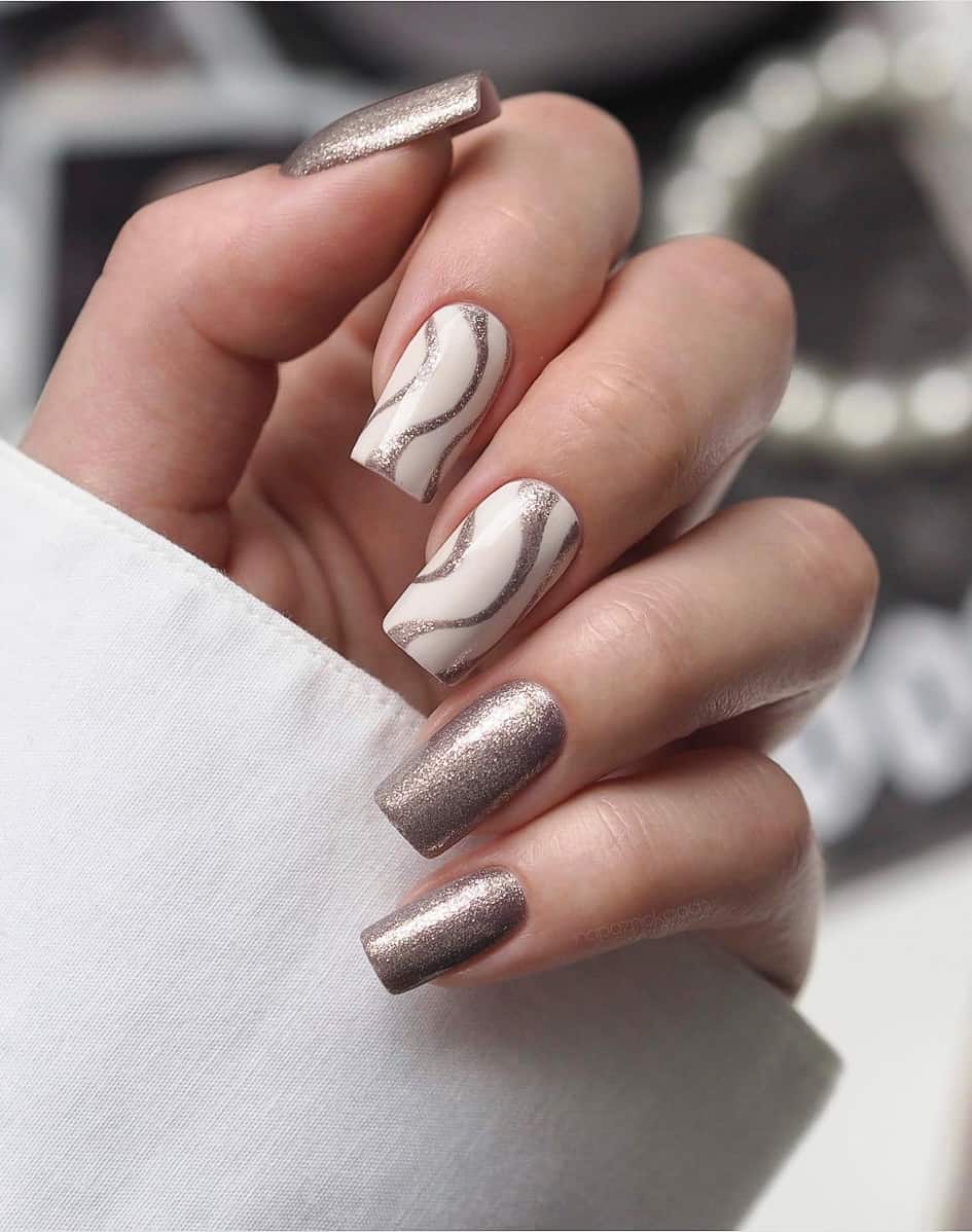 image of a hand with white nails with silver glitter accents