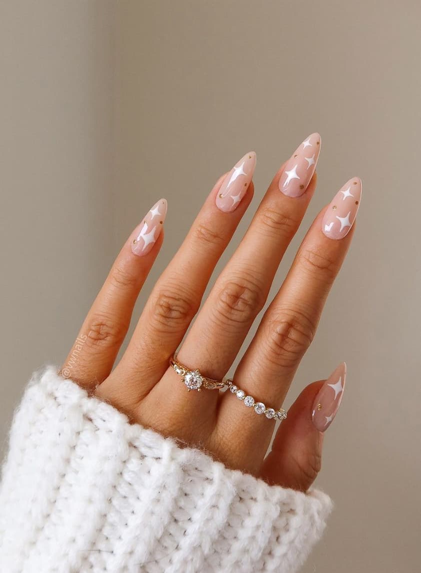 image of a hand with nude nails with white and gold star accents