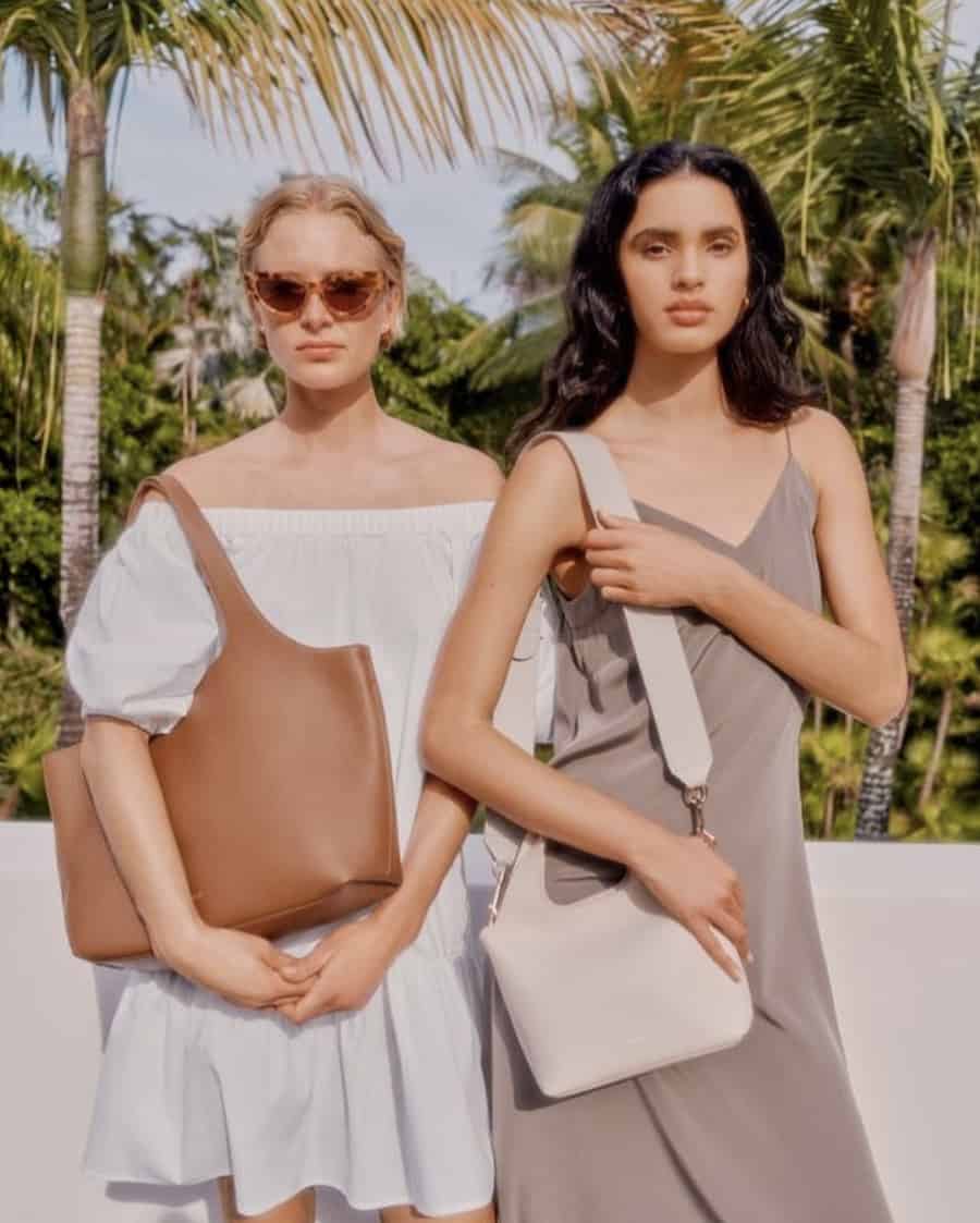 two women wearing neutral dresses with neutral leather tote bags