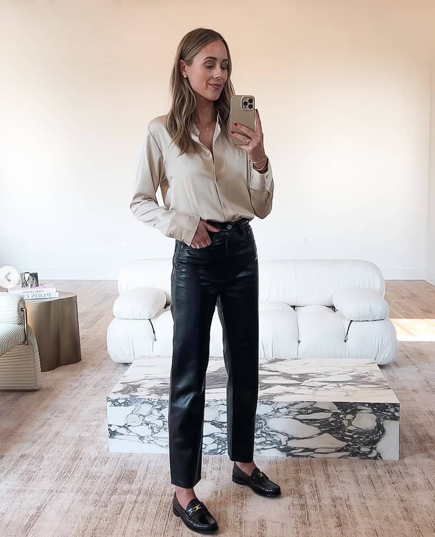 woman wearing a nude silk button down blouse with black leather pants and black loafers