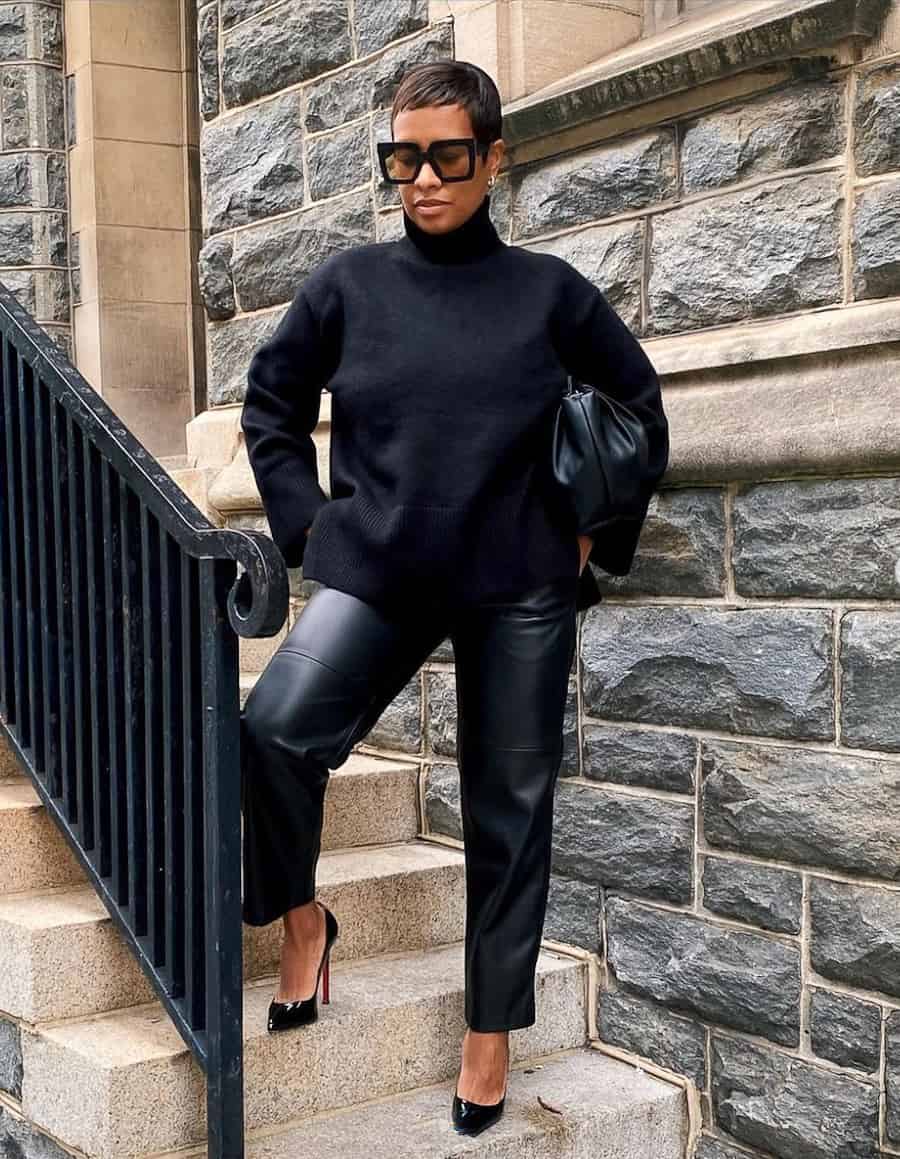 black woman wearing a black turtleneck, black leather pants, and black pumps