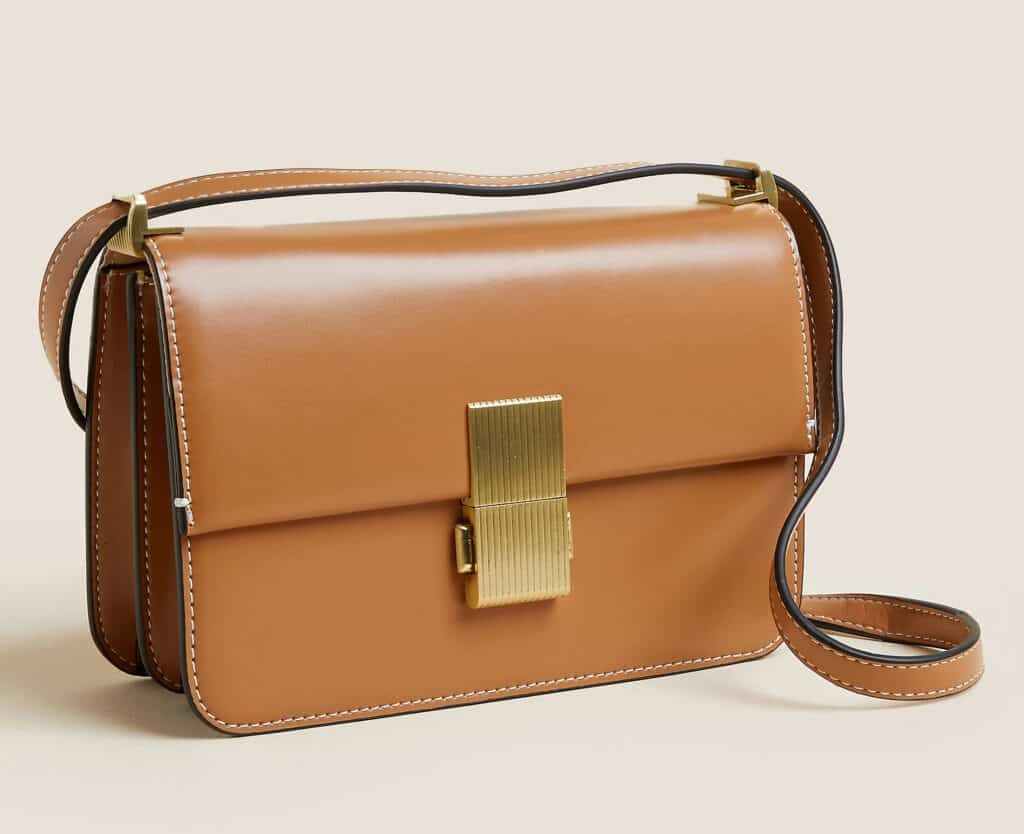 Image of a brown faux leather box bag in a camel color tone with a gold clasp in the center