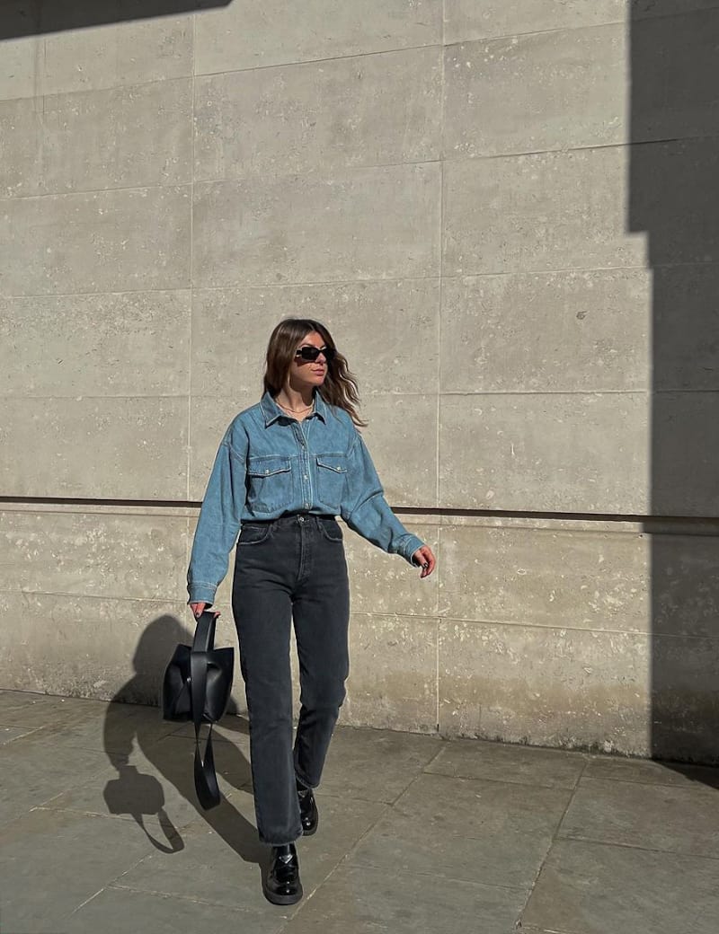 image of a woman in a blue denim button up shirt, black jeans, and black chunky shoes
