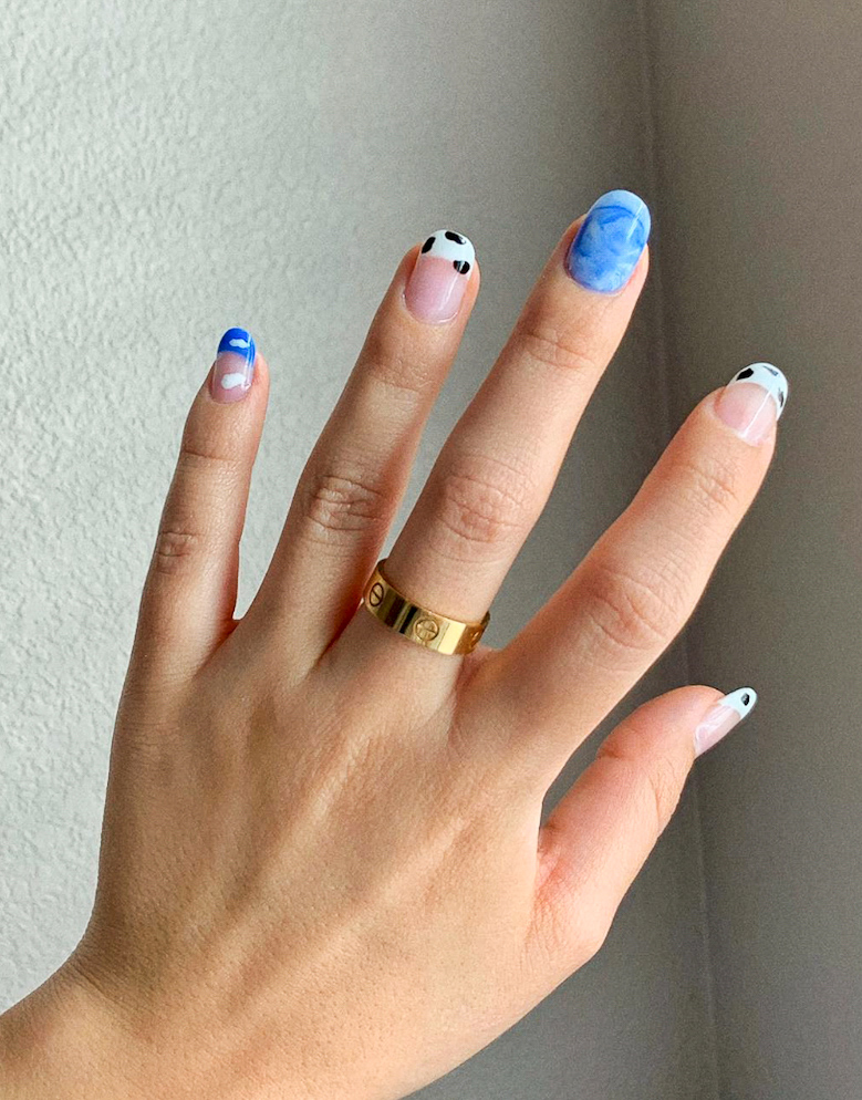 a hand with blue nails with black and white cow print accents