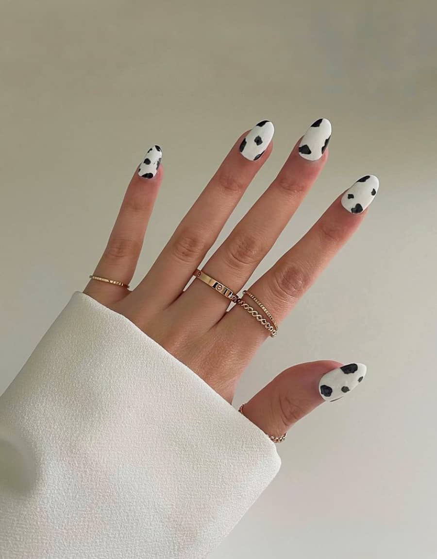 a hand with white nails with a minimal cow print design