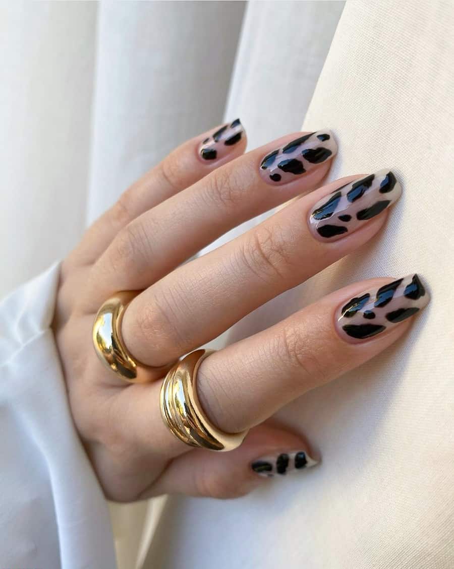 a hand with a clear and black cow print nail design 
