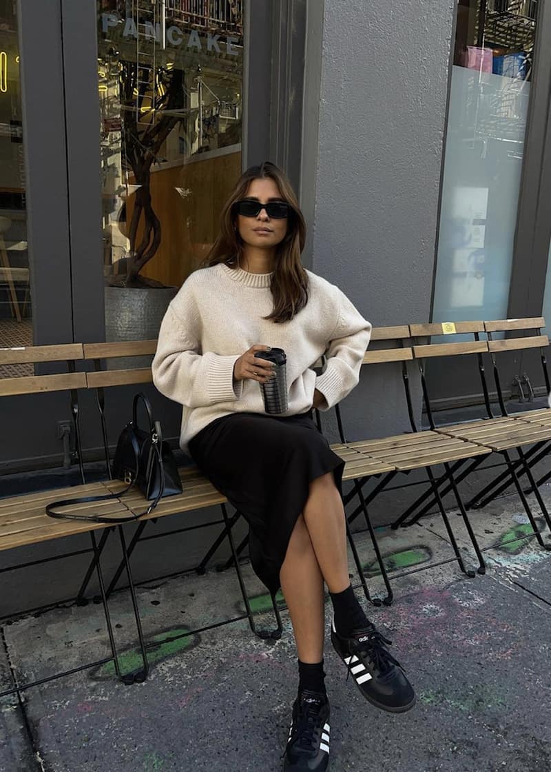 woman wearing a cozy knit sweater, midi skirt and sneakers