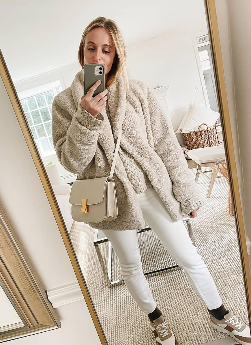 woman wearing an ivory teddy coat with white jeans, socks and sneakers