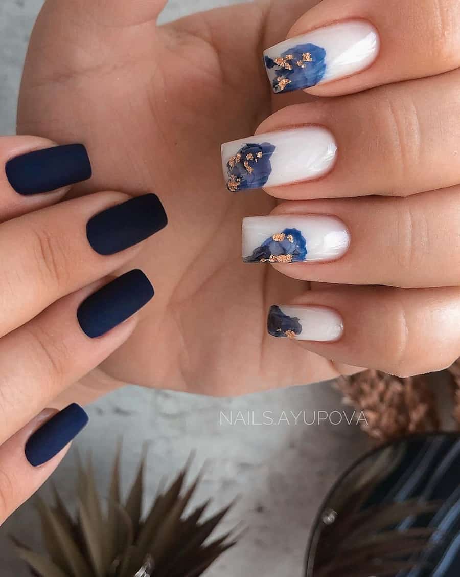 two hands with dark blue and white nails with navy designs