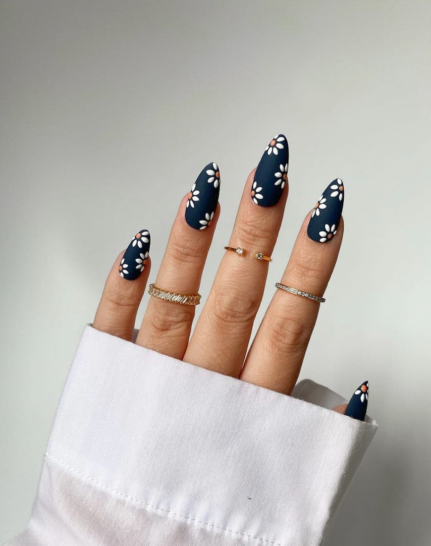 hand with dark blue nails with floral designs