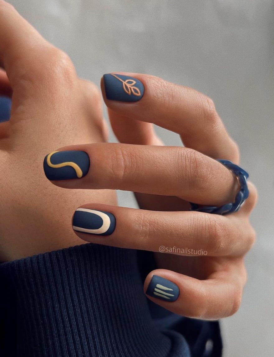 hand with dark blue nails with gold designs