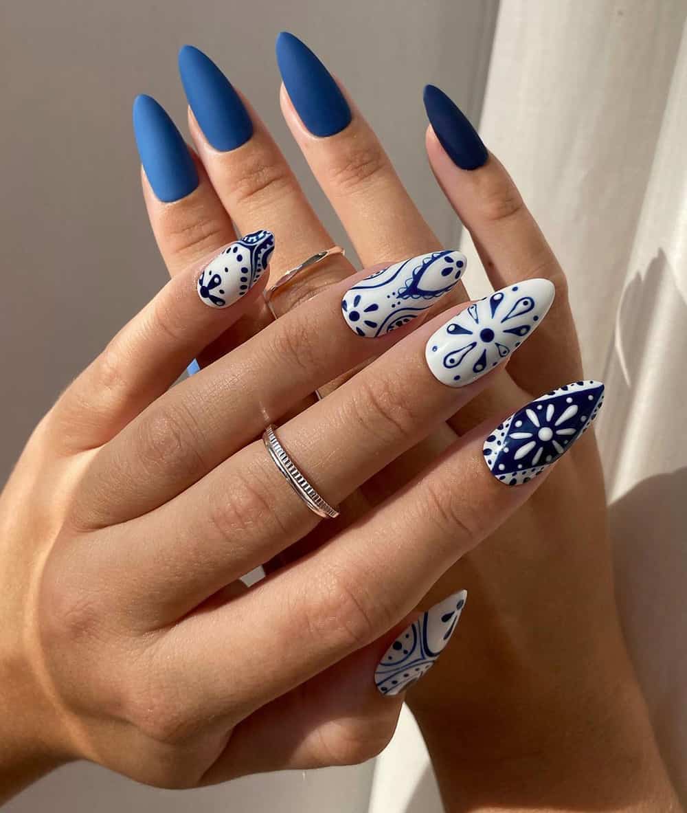hands with dark blue polish and Moroccan tile white and blue art