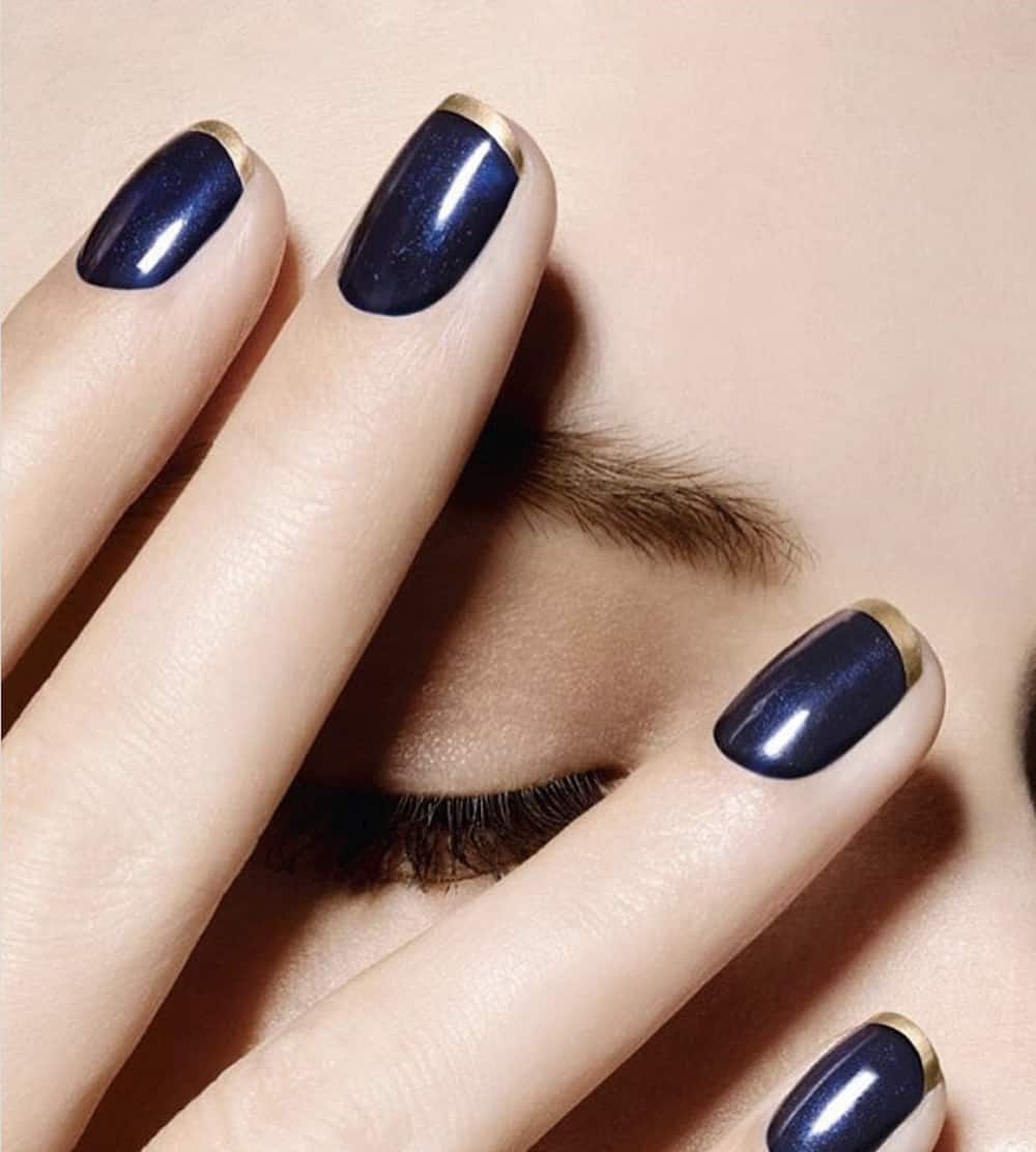 hand with navy blue nails over a womans face