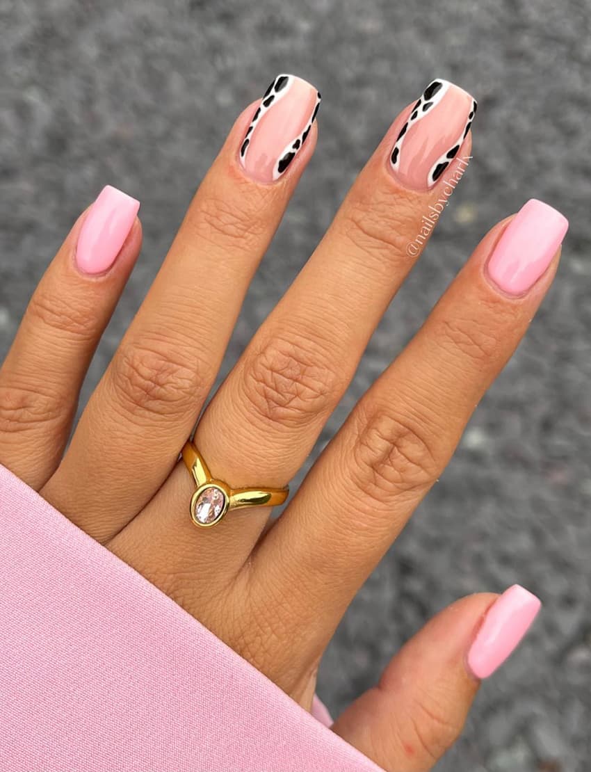 image of a hand with square pink nails with minimal cow print accents