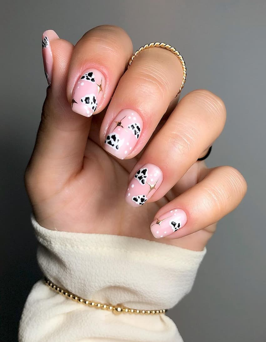 hand with pink nails with clouds in a white and black cow print