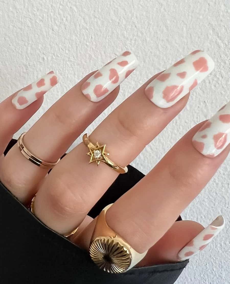 hand with white and baby pink cow print design on the nails