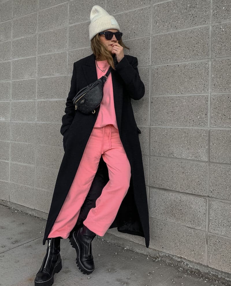 woman wearing a matching pink sweatsuit with a black wool coat and black boots