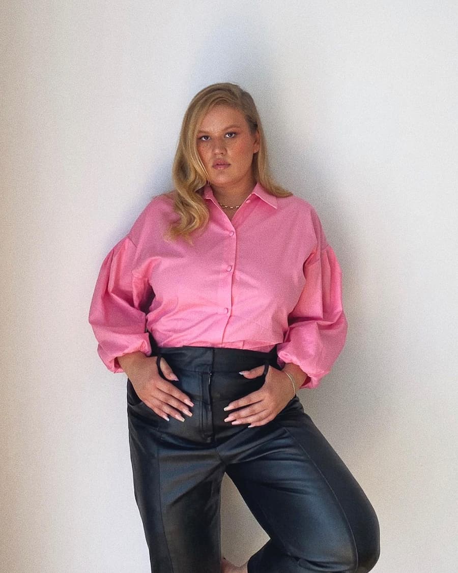 plus size woman wearing a pink button-up shirt with black pants