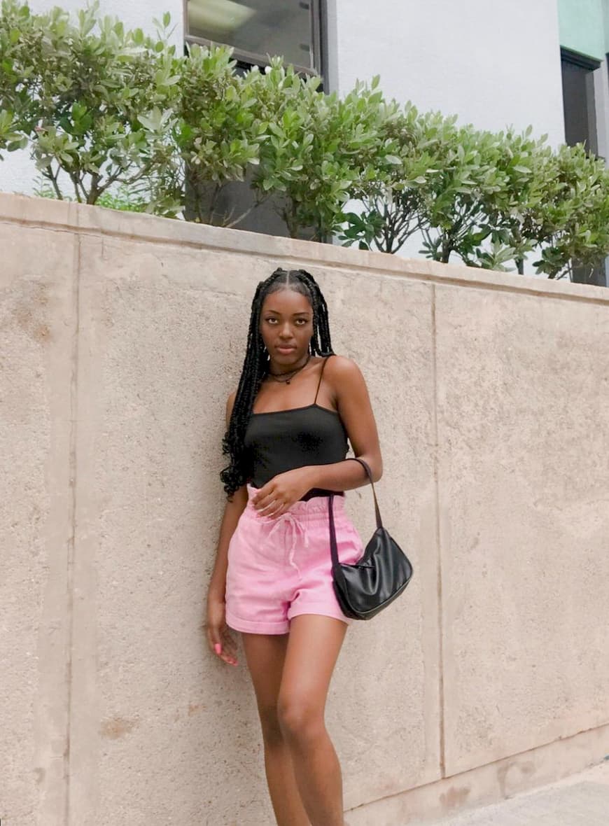 black woman wearing a black tank top and light pink shorts