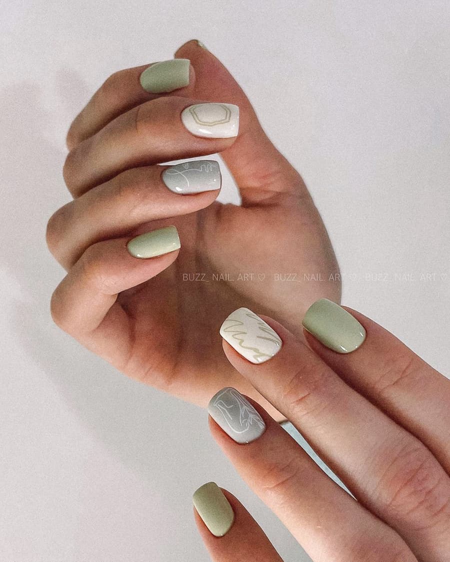 two hands with sage green and neutral nail polish and leaf accents