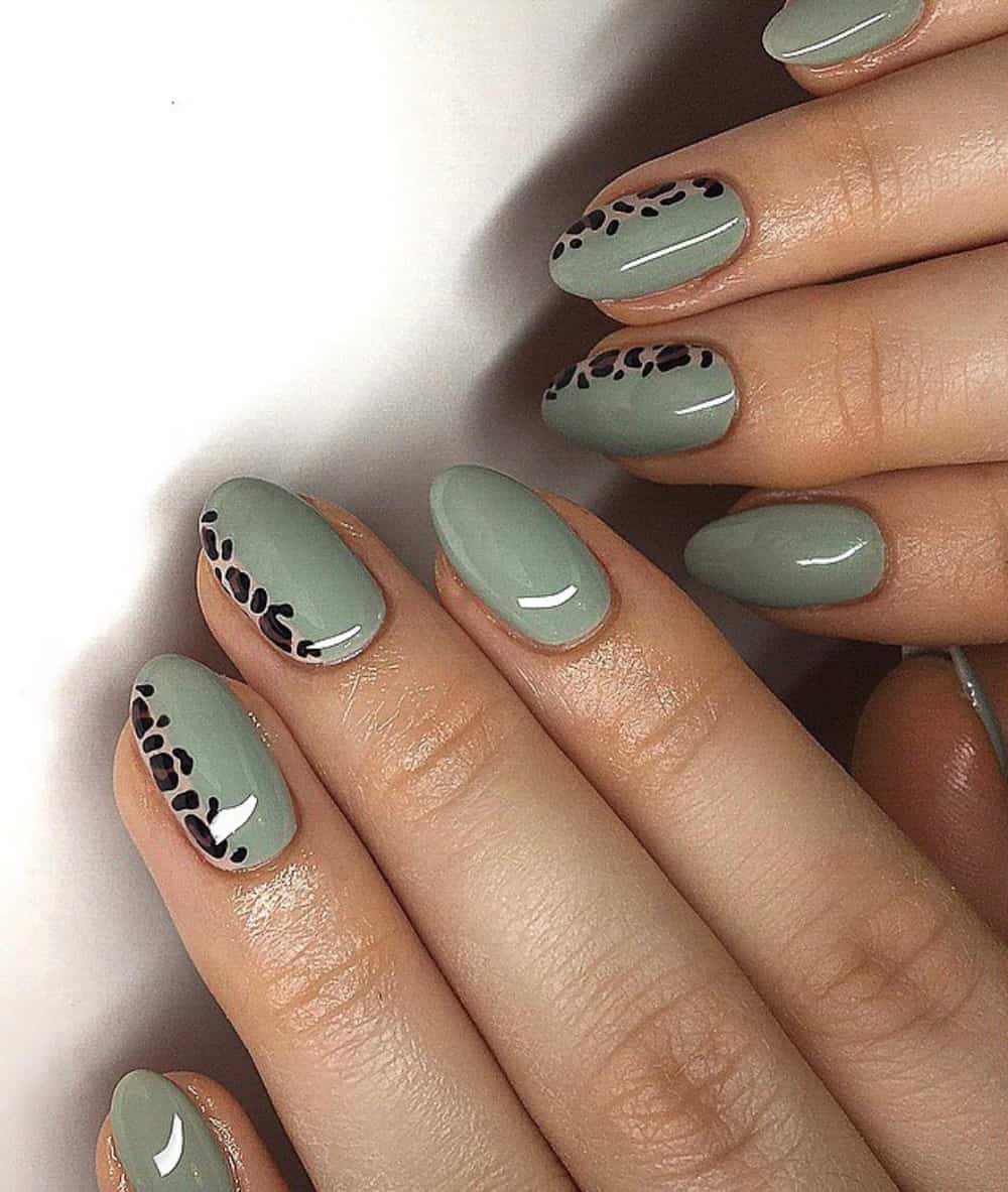 hands with sage green and leopard nail art