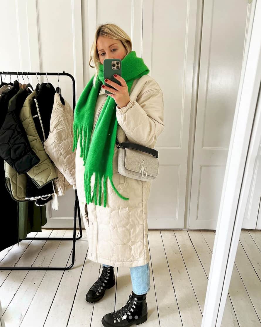 woman wearing a bright green scarf over a long white quilted puffer coat